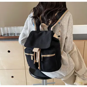 Detalle de una mochila vintage de lona negra con correas beige y cierre de cordón