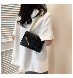 Detail shot of black flap bag with gold metal trim and chain strap on a model