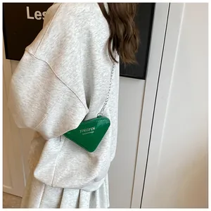 Mini sac triangle vert brillant avec chaîne argentée porté par un mannequin