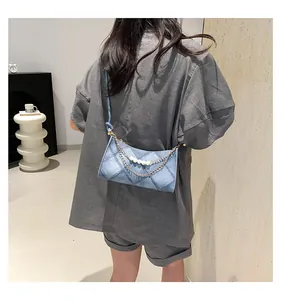 Détail d'un sac bandoulière en denim matelassé bleu avec chaîne perlée et bandoulière