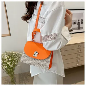 Detail view of the orange faux leather and straw woven bag with silver metallic twist lock