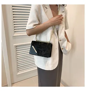Close-up of black square crossbody bag with gold chain strap and geometric pattern