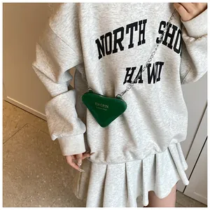 Détail d'un mini sac triangle vert fluo avec une chaîne argentée et un fini brillant