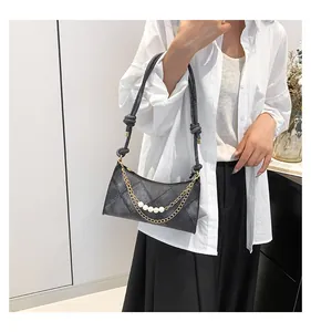 Détail du sac à bandoulière matelassé noir avec sangle tissée, chaîne dorée et perles