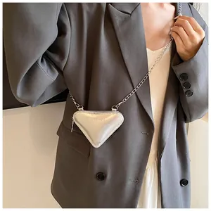 Détail d'un mini sac triangle argenté à chaîne porté sur un blazer gris élégant