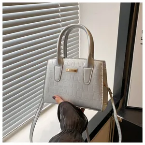 Detail view of silver crocodile pattern handbag with metal plate and double handles