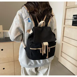 Mochila tipo cubo de lona negra con correas de contraste mostrada por una modelo