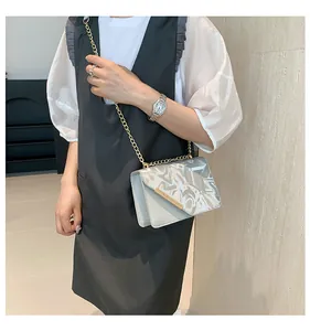Detailed view of the stylish silver crossbody bag with gold chain and artistic letter print