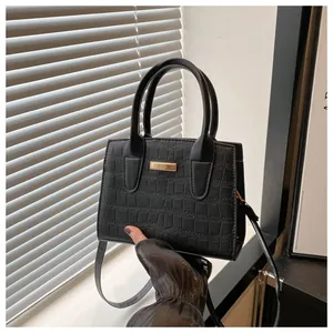 Detail of black stone-embossed tote bag with golden metal plate and textured leather
