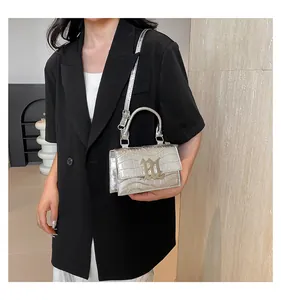 Silberne Handtasche mit Krokomuster zu schwarzem Anzug für einen minimalistischen Look