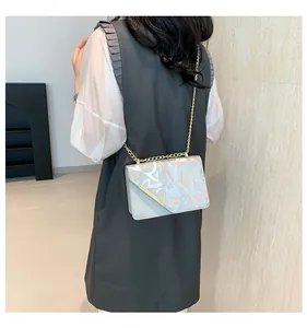 Silver chain crossbody bag with graffiti print and gold V-shaped metal trim detail