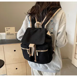 Detalle de mochila tipo saco de lona negra con correas beige y cremalleras doradas