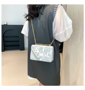 Detail view of silver grey crossbody bag with artistic graffiti print and gold chain strap