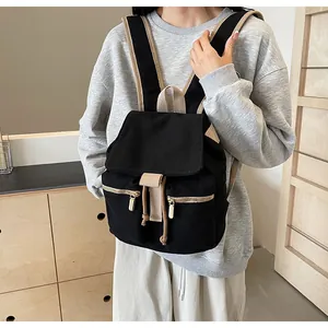 Detalle de mochila de lona negra con correas beige y cremalleras metálicas en un interior