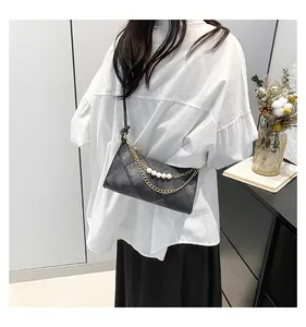 Détail du sac à bandoulière noir matelassé avec perles élégantes et chaîne dorée