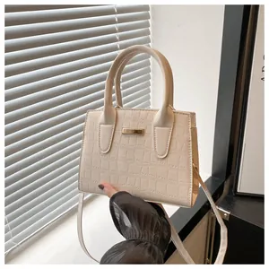 Close-up of beige stone-textured handbag with gold metal hardware and structured handles