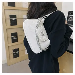 Detail of white marble textured shoulder bag with silver butterfly and metal chain