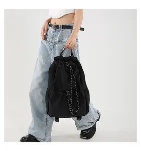 Détail d'un sac à dos en nylon noir avec cordons de serrage rayés et poches latérales