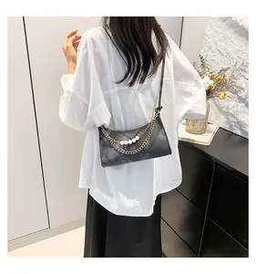 Détail du sac bandoulière noir matelassé avec des accents de perles et de chaîne
