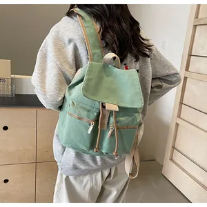 Detalle de la mochila de lona verde claro con cordón y bolsillos con cremallera