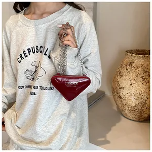 Détail d'un sac à bandoulière triangulaire rouge en cuir PU avec chaîne argentée