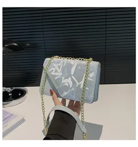 Detailed shot of light blue square crossbody bag with graffiti print and gold chain