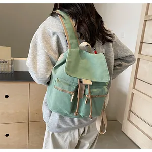 Detalle de mochila de lona verde claro con tirantes acolchados y cremalleras metálicas