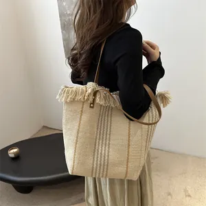 Bolso tote grande de tejido con rayas marrones y borlas en una vista lateral de estilo