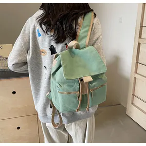 Detalle de la mochila de lona verde menta con correas caqui y bolsillos con cremallera