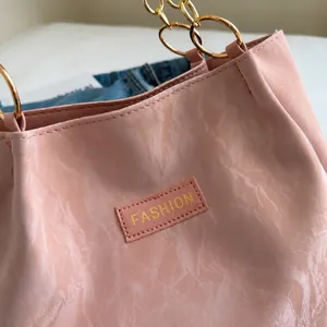 Dettaglio della borsa in pelle rosa plissettata con anello dorato e logo Fashion