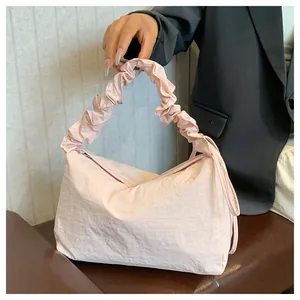 Detail der hellrosa gefalteten Handtasche mit gerafftem Griff und feiner Nylontextur