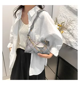 Détail du sac en jean gris avec chaînes dorées perlées et texture matelassée