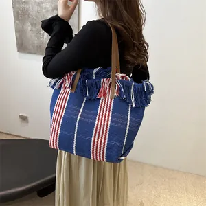 Bolso tote de tejido grande con rayas y borlas de colores usado por una modelo