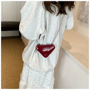 Détail du petit sac bandoulière triangulaire en cuir verni rouge avec chaîne argent