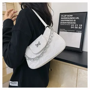 Detail of white marble textured shoulder bag with silver butterfly clasp and metal chain