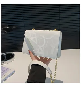 Close-up of white patterned shoulder bag with gold chain strap and metal trim details