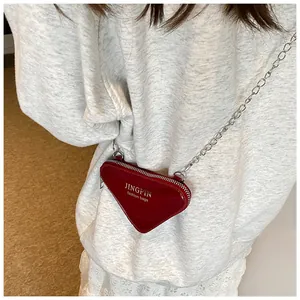 Détail du sac bandoulière triangulaire en cuir verni rouge avec bandoulière chaîne