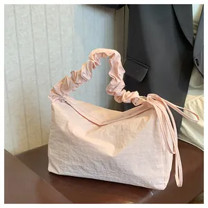 Detail der hellrosa gefalteten Canvas-Schultertasche mit gerafftem Griff und Bändern