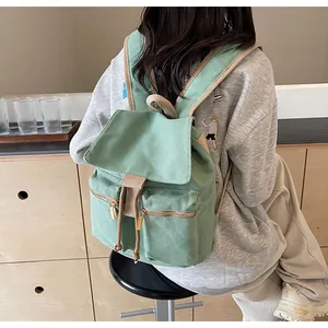 Detalle de mochila de lona verde con cordón y dos bolsillos frontales con cremallera
