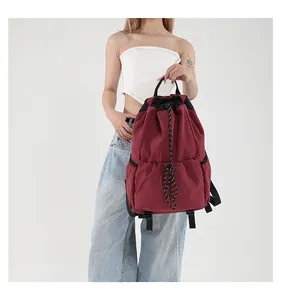 Gros plan du sac à dos en nylon bordeaux avec cordon de serrage et poches latérales
