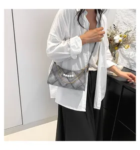 Sac en denim gris matelassé avec chaînes dorées et perles porté par un mannequin femme