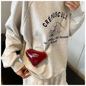 Gros plan d'un mini sac bandoulière rouge en forme de cœur avec chaîne sur modèle