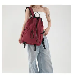 Sac à dos bordeaux en nylon avec cordon de serrage porté par un modèle, style sport