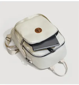 Detail view of large beige leather backpack showing a tablet inside for size reference