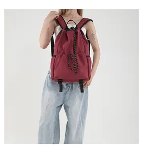 Détail d'un sac à dos en nylon bordeaux avec cordon de serrage, texture et boucle réglable