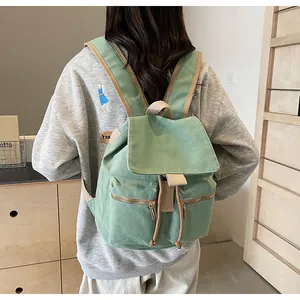 Detalle de mochila de lona verde claro con cordón ajustable y correas de hombro acolchadas