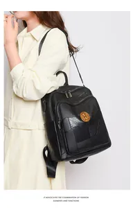 Detailed macro view of black pebbled leather backpack with gold crest and zipper pockets