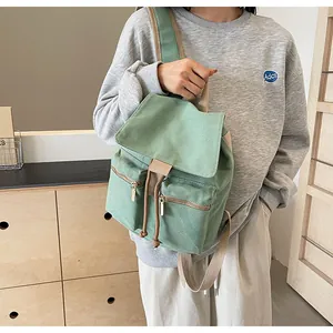 Detalle de la mochila tipo cubo de lona verde salvia con cordón y bolsillos con cremallera