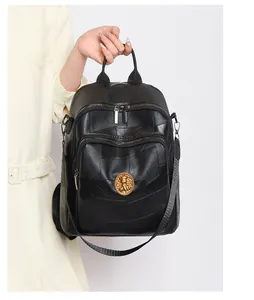 Detail of black textured leather backpack with a round gold emblem and zipper pockets