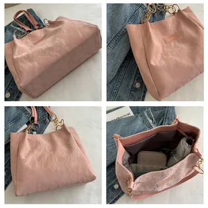 Detail van lichtroze geplooide shopper met fashion-label en gouden ketting